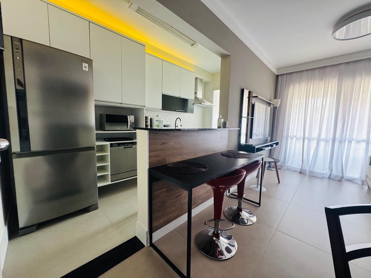 Cozinha americana integrada à sala, com bancada e banquetas
