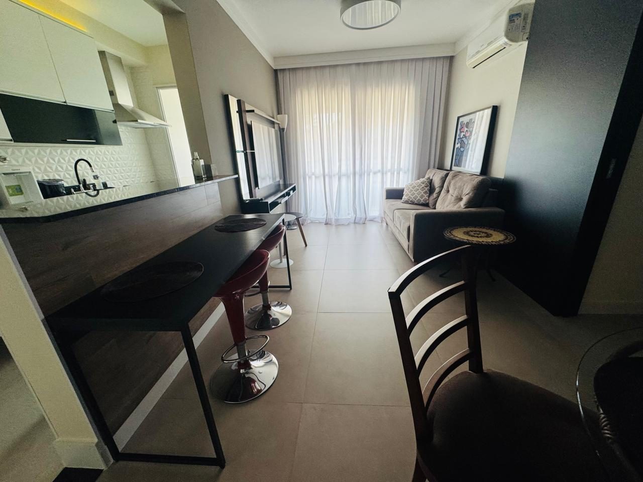 Sala de estar vista da bancada, com sofá, TV e varanda