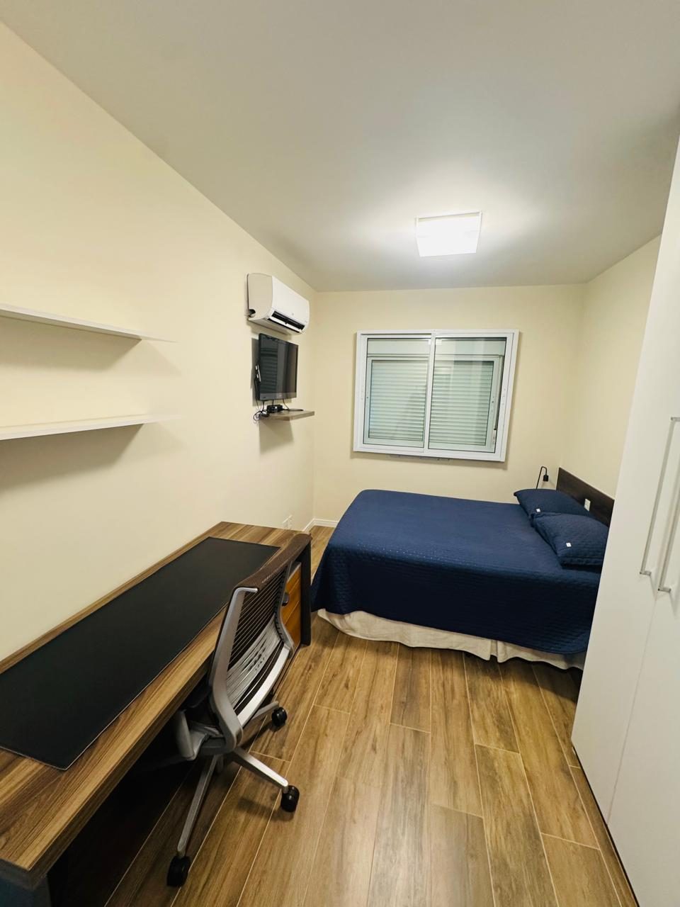 Suíte com cama de casal, mesa de trabalho, TV e ar-condicionado